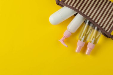 Parlak sarı bir arka plan üzerinde bir kozmetik çantası seyahat için kozmetik ve kişisel bakım ürünleri bir dizi. üst görünüm. seyahat kozmetik