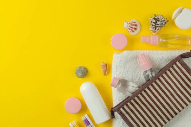 Parlak sarı bir arka plan üzerinde bir kozmetik çantası seyahat için kozmetik ve kişisel bakım ürünleri bir dizi. üst görünüm. seyahat kozmetik