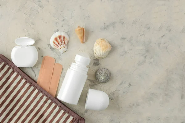 A set of cosmetics and personal care products for travel in a cosmetic bag on a light concrete background. top view. travel cosmetics