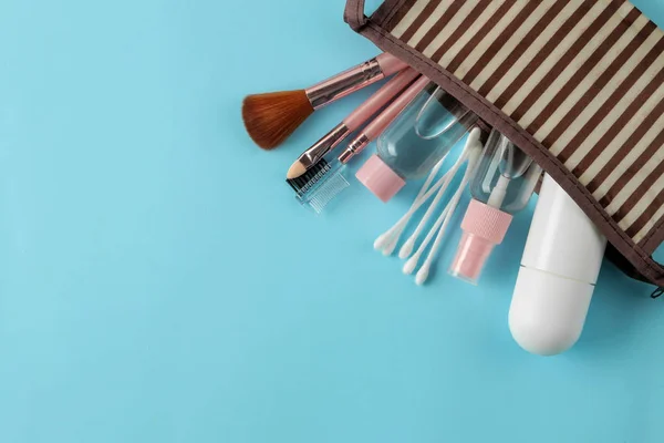 A set of cosmetics and personal care products for travel in a cosmetic bag on a light blue background. top view. travel cosmetics