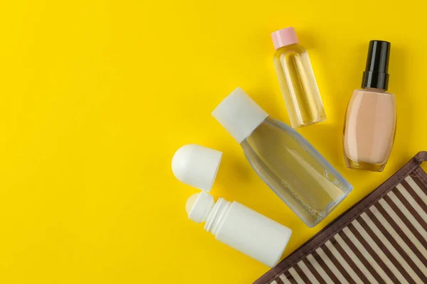 A set of cosmetics and personal care products for travel in a cosmetic bag on a bright yellow background. top view. travel cosmetics