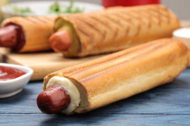 Fransız sosislileri. Tahtada lezzetli sosisli sandviç ve mavi ahşap bir masaüzerinde sos. fast food sokak gıda. bir topuzun içinde sosis.