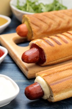 Fransız sosislileri. Tahtada lezzetli sosisli sandviç ve mavi ahşap bir masaüzerinde sos. fast food sokak gıda. bir topuzun içinde sosis.