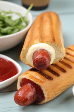 Fransız sosislileri. Açık mavi ahşap masada lezzetli sosisli sandviç ve ketçap. fast food sokak gıda. bir topuzun içinde sosis.