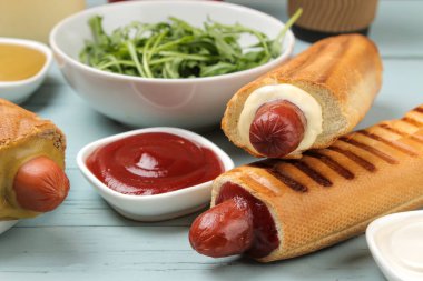 Fransız sosislileri. Açık mavi ahşap masada lezzetli sosisli sandviç ve ketçap. fast food sokak gıda. bir topuzun içinde sosis.