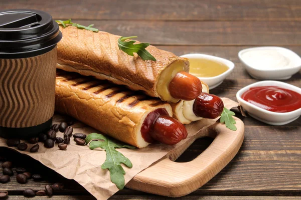 Fransız sosislileri. Tahtada lezzetli sosisli sandviç ve kahverengi ahşap bir masada kahve. fast food sokak gıda. bir topuzun içinde sosis.