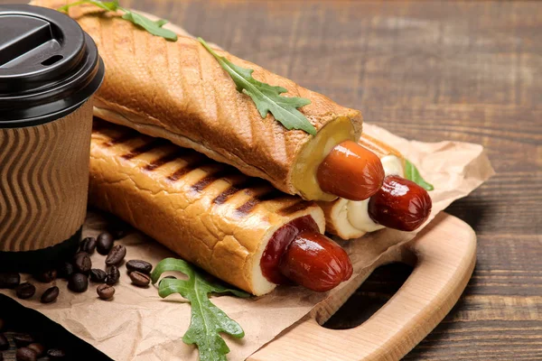 Fransız sosislileri. Tahtada lezzetli sosisli sandviç ve kahverengi ahşap bir masada kahve. fast food sokak gıda. bir topuzun içinde sosis.