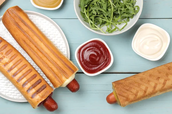 Fransız sosislileri. Lezzetli sosisli sandviç ve hardal, mayonez, açık mavi ahşap masa üzerinde ketçap. fast food sokak gıda. bir topuzun içinde sosis. üst görünüm