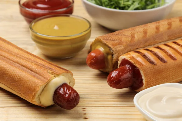 Fransız sosislileri. Doğal ahşap bir masa üzerinde lezzetli sosisli sandviç ve ketçap, mayonez ve hardal. fast food sokak gıda. bir topuzun içinde sosis.
