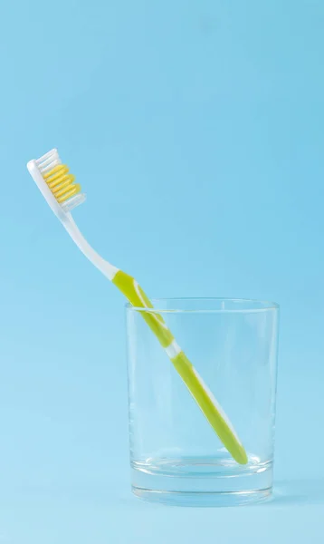 Igiene Orale Spazzolino Denti Verde Bicchiere Uno Sfondo Blu Delicato — Foto Stock