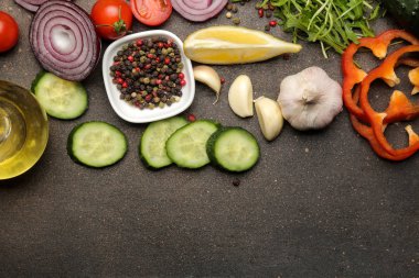 Yemek salatası için malzemeler. Çeşitli sebze ve baharatlar havuç, domates, soğan, salatalık, biber ve koyu bir arka plan üzerinde arugula. üst görünüm.