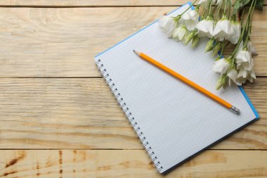 Doğal ahşap bir masa üzerinde bir kalem ve beyaz çiçekler ile Defter. üst görünüm
