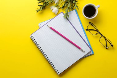 birkaç dizüstü bilgisayar ve gözlük parlak sarı bir arka plan üzerinde kahve ve çiçek bir fincan. üst görünüm. ofis araçları