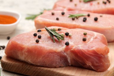 Tahtada çiğ domuz biftek, et ve pişirme için malzemeler, baharat otlar ve hafif bir arka plan üzerinde sebze. Close