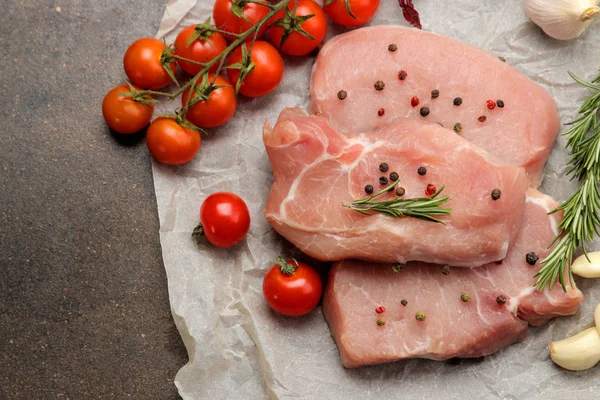 Çiğ domuz biftek, et ve pişirme için malzemeler, baharatlar, otlar ve koyu bir arka plan üzerinde sebze. üst görünüm.