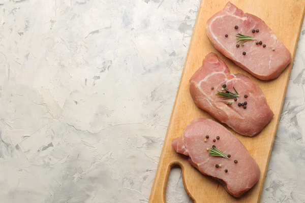 Tahtada çiğ domuz biftek, et ve pişirme için malzemeler, baharat otlar ve hafif bir arka plan üzerinde sebze. üst görünüm. metin için alan