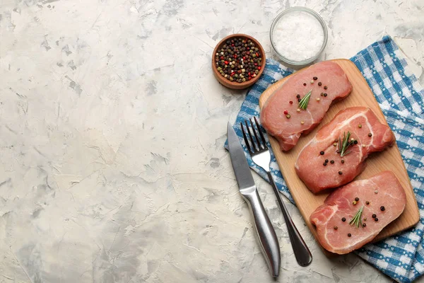 Tahtada çiğ domuz biftek, et ve pişirme için malzemeler, baharat otlar ve hafif bir arka plan üzerinde sebze. üst görünüm. metin için alan