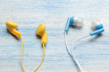 Açık mavi ahşap arka plan üzerinde küçük çeşitli çok renkli kulaklıklar.