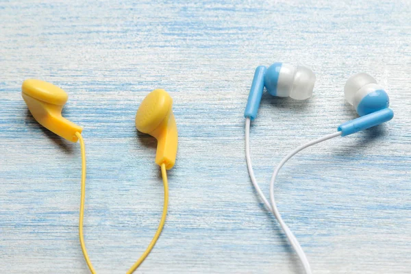 Açık mavi ahşap arka plan üzerinde küçük çeşitli çok renkli kulaklıklar.