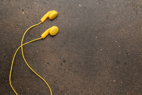 Koyu renkli arka plandaki bir akıllı telefon için küçük sarı kulaklıklar. üst görünüm. metin için alan