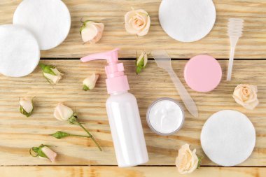 yüz ve vücut için kozmetik. Doğal ahşap arka plan üzerinde taze gül ile pembe şişelerde Krem. kremler ve losyon. Spa. üst görünüm
