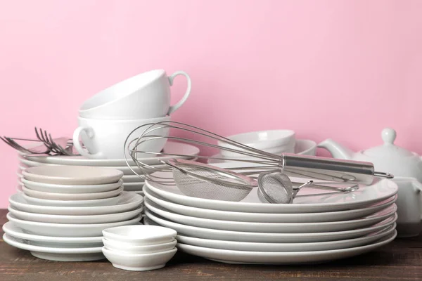 Piles of white ceramic tableware, plates, saucers, cups on a pink background. kitchenware.