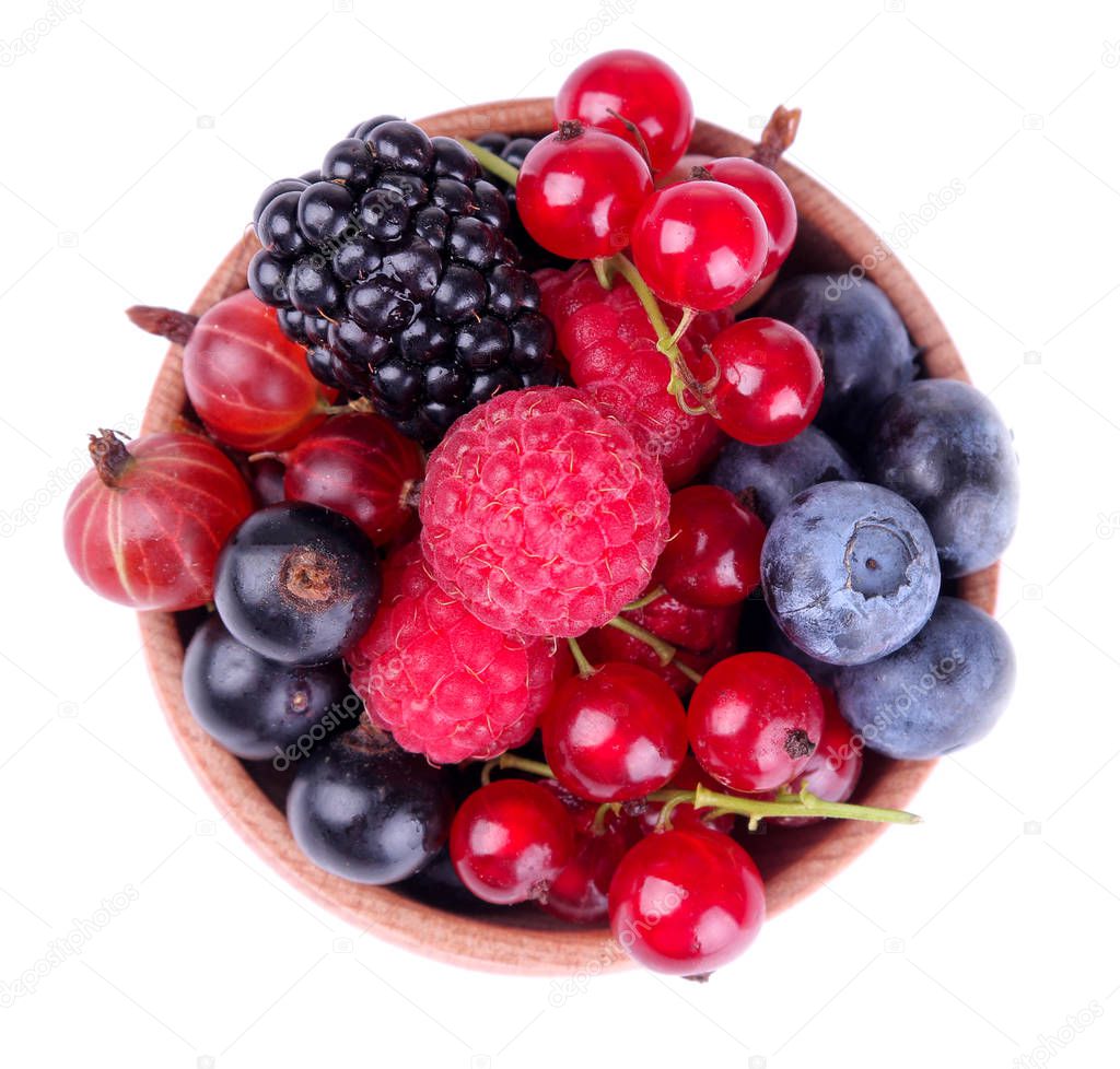 Tasty berries in a wooden bowl, currants, blackberries, blueberries, raspberries on a white isolated background. top view