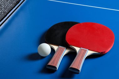 İki ping pong raket. Masa tenisi raketleri ve mavi tenis masasında bir top