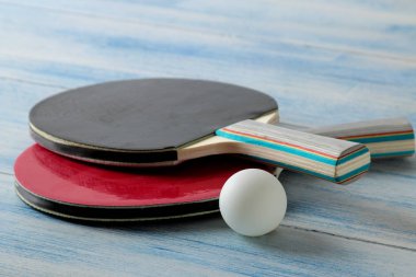 İki ping pong raket. Masa tenisi raketleri ve mavi ahşap masada bir top. spor oyunu.
