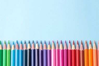 Parlak mavi bir arka plan üzerinde renkli kalemler ile kompozisyon. üstten görünüm. text.frame mekanı