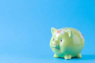 Parlak mavi arka planda yeşil domuz para kutusu. Finans, tasarruf, para. metin için alan