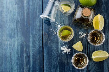 Mavi ahşap bir masada tuz ve kireç ile bir bardak altın tekila. alkollü içecekler. üst görünüm