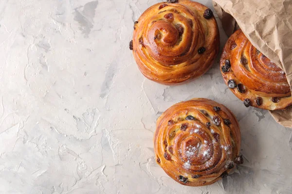 Delicious buns with raisins in a package on a light concrete table. fresh bakery. breakfast. bread. top view