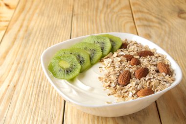 Doğal ahşap masada kivi badem ve yulaf ezmesi ile Yunan beyaz yoğurt. Kahvaltı. sağlıklı gıda