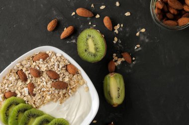 Koyu grafit masada kivi badem ve yulaf ezmesi ile Yunan beyaz yoğurt. Kahvaltı. üst görünüm. sağlıklı gıda