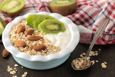 Koyu kahverengi bir masada kivi badem ve yulaf ezmesi ile Yunan beyaz yoğurt. Kahvaltı. sağlıklı gıda