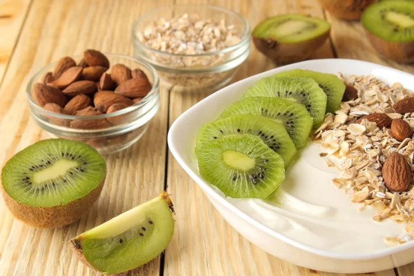 Doğal ahşap masada kivi badem ve yulaf ezmesi ile Yunan beyaz yoğurt. Kahvaltı. sağlıklı gıda
