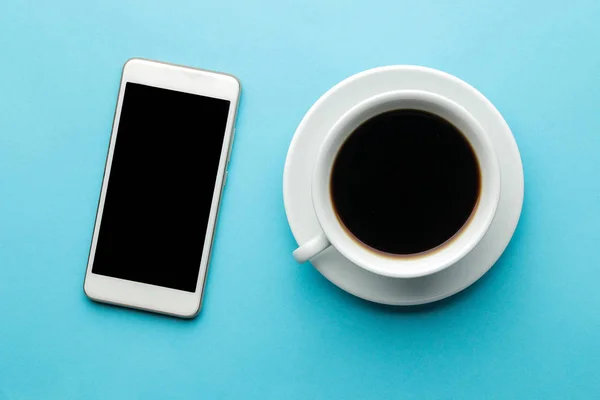 Smartphone Weißes Telefon Und Eine Tasse Kaffee Auf Hellblauem Hintergrund — Stockfoto