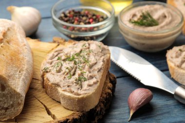 Mavi ahşap bir masada ekmek üzerinde otlar ile taze ev yapımı tavuk ciğeri pate. Sandviç. Close