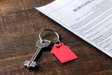 ipotek uygulaması. Anahtar kırmızı anahtarlık ev ve kahverengi ahşap bir masa üzerinde boş. bir ev satın alma kavramı.