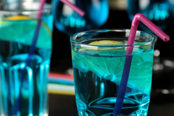 Cocktail blue lagoon in a cocktail glass with lemon and mint on a brown dark table in a bar. bar accessories.