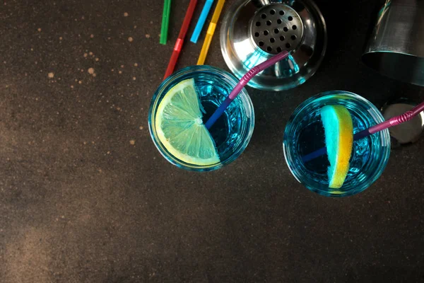 Cocktail blue lagoon in a cocktail glass with lemon and mint on a brown dark table in a bar. bar accessories. top view