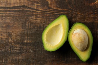 Kahverengi ahşap arka plan üzerinde taze olgun lezzetli avokado. tropikal meyve üst görünümü. metin için alan