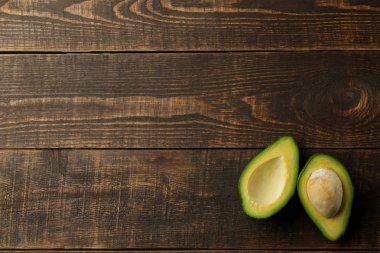 Kahverengi ahşap arka plan üzerinde taze olgun lezzetli avokado. tropikal meyve üst görünümü. metin için alan