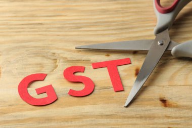 Doğal ahşap bir masa üzerinde kağıt harfler ve makas kelime Gst. Vergi 