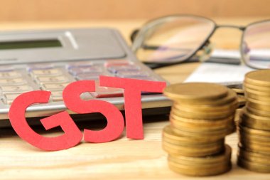 Kağıt harfler ve sikkeler ve doğal ahşap bir masa üzerinde bir hesap makinesi kelime Gst. Vergi