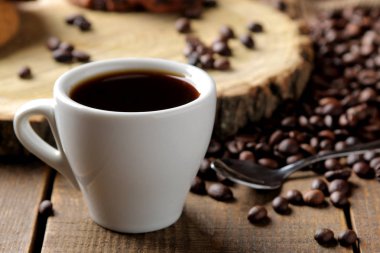 Kavrulmuş kahve taneleri ve kahverengi ahşap arka plan üzerinde bir fincan kahve. Robusta, Arabica.