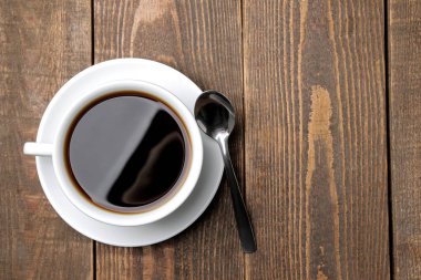 Beyaz bir fincan ve kahverengi ahşap bir masa üzerinde kaşık kahve. üst görünüm. metin için alan