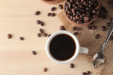 Doğal ahşap bir masada beyaz bir fincan ve kavrulmuş kahve taneleri kahve. Robusta, Arabica. üst görünüm