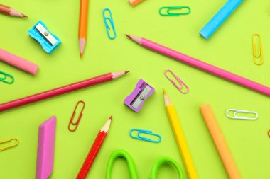 çeşitli okul malzemeleri kalemleri, kağıt klipler, parlak yeşil arka plan üzerinde boya kalemi arka plan. Ofis araçları. Eğitim. üst görünüm.